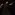 In golden light, a man with short dark hair, wearing a long black shirt over a full black skirt, looks upwards, his arms forming a sinuous s-shape: the right arm is twisted elbow up, hand pointing downwards, the left arm is lifted in a curve, the hand pointing upwards.