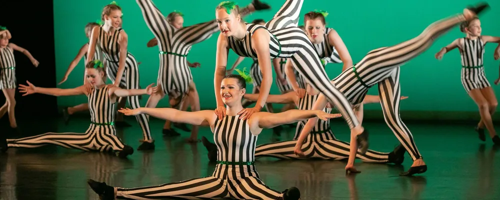 A dance group of teenagers performing a routine on stage