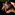 A male dancer wearing a wooden mask holds his hands up to his face
