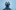 Close‑up of a performer with a lifted chin against a pale blue background.