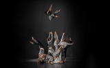 Group of acrobatic dancers with one performer thrown high into the air.