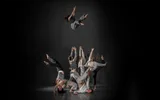 Group of acrobatic dancers with one performer thrown high into the air.